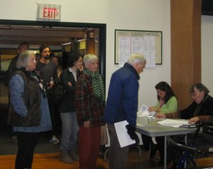 Voters check in with the registrars as they enter the gym. IDs are not required. You'd have a hard time passing yourself off as anyone else, and unless you can clone yourself, you can't vote twice.