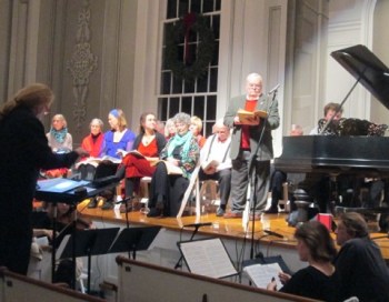 Warming up before the performance. The sopranos are in front, the basses behind. Conductor Wes Nagy is at far left, bass soloist Glenn Carpenter is standing up, and Griffin McMahon is partly visible at the piano.